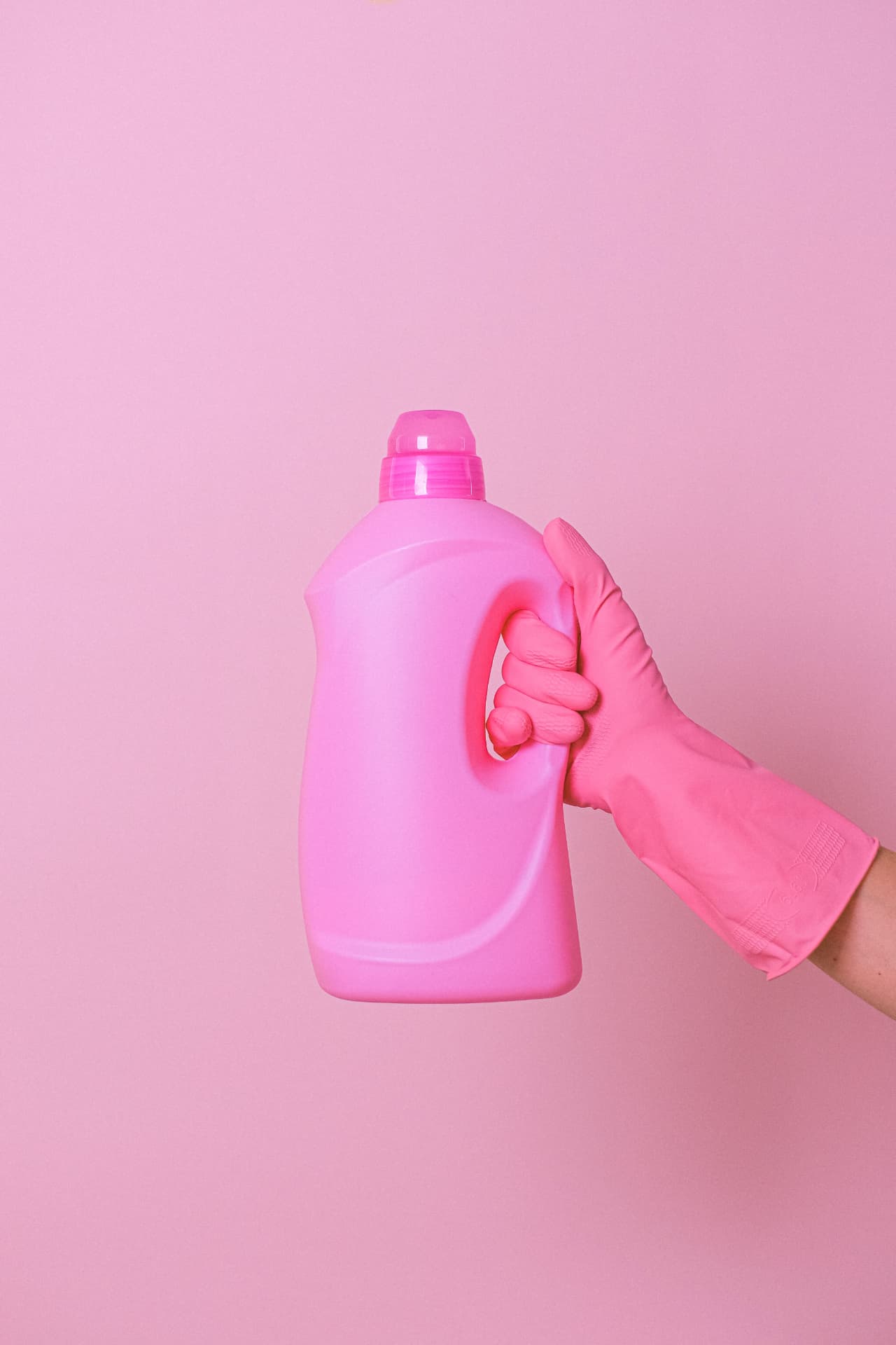Gloved hand holding a bottle of cleaning solution