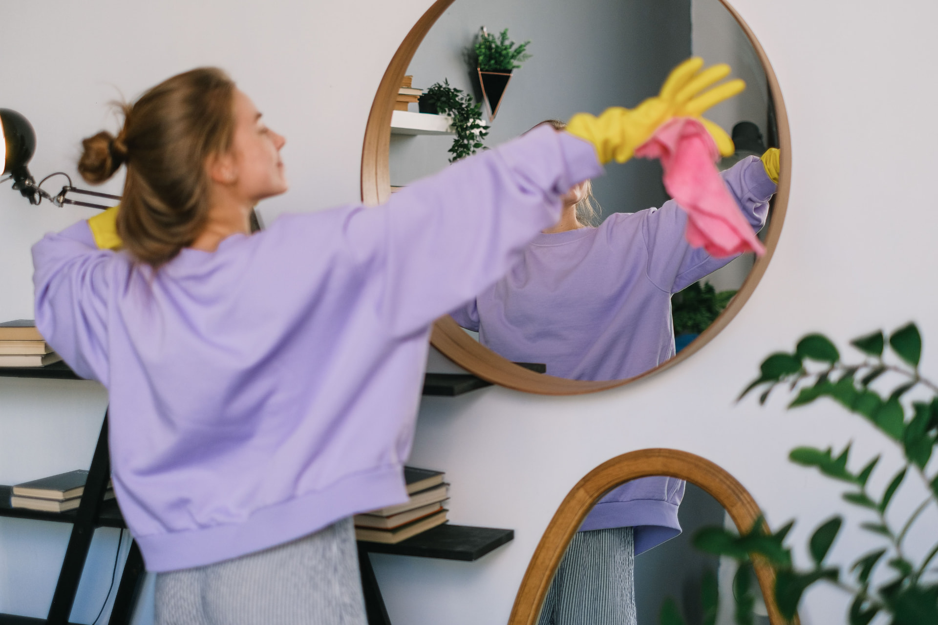 Cleaner polishing a round wall mirror streak-free