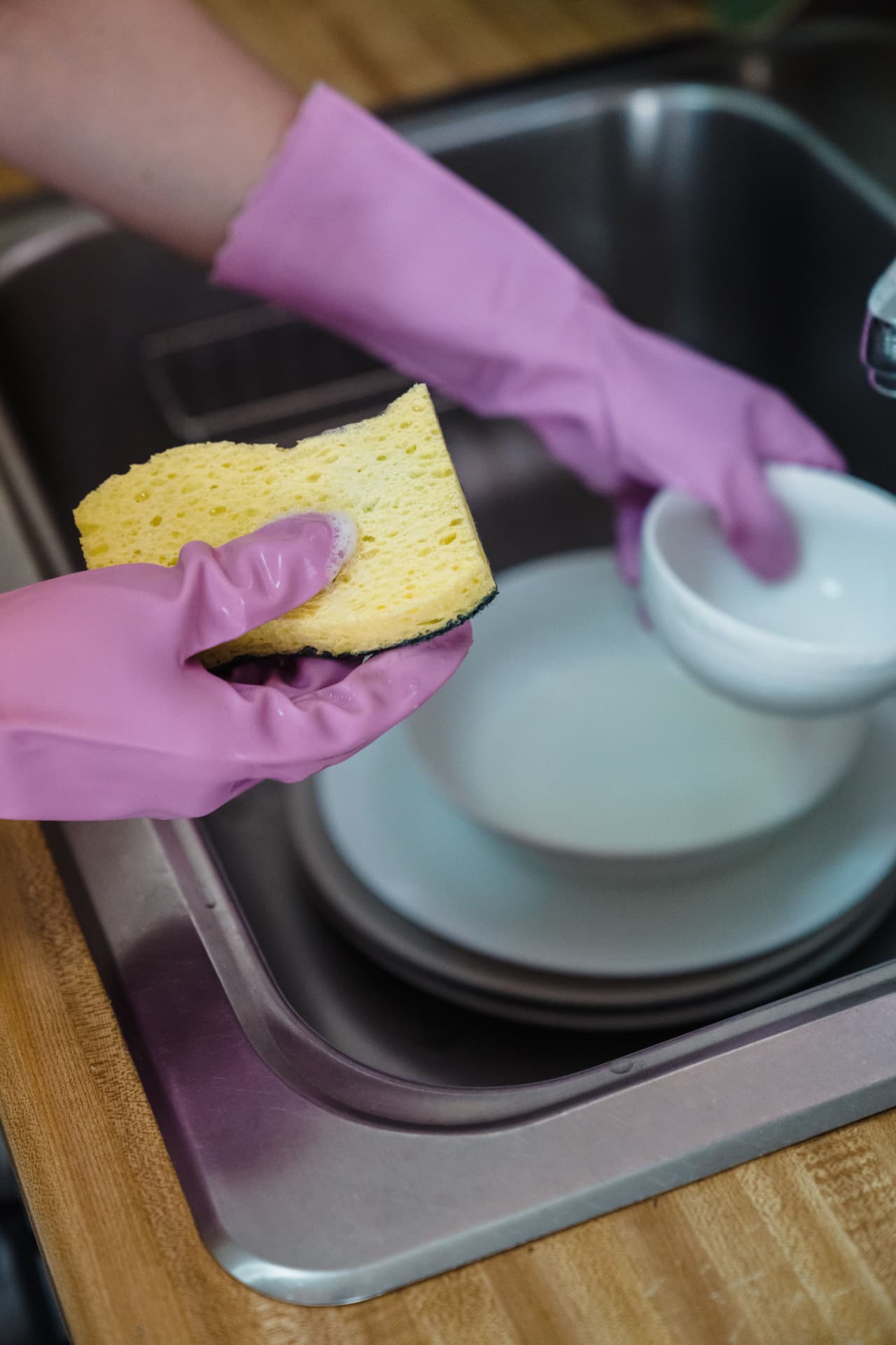 Cleaner in purple gloves washing dishes