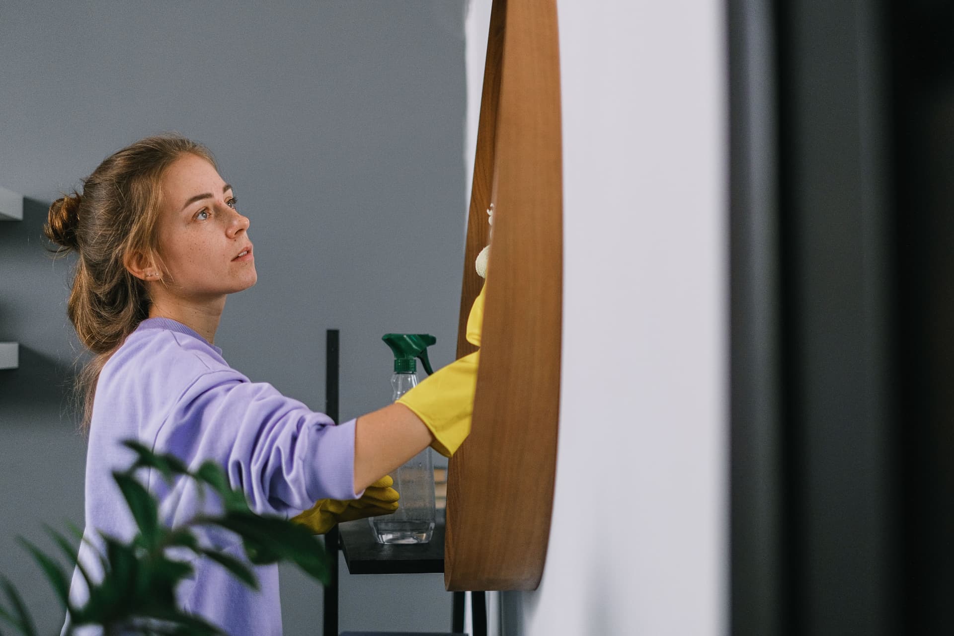 Cleaner detailing a mirror frame with spray and cloth
